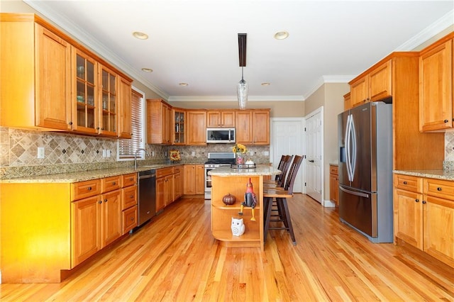 kitchen with appliances with stainless steel finishes, light wood-type flooring, tasteful backsplash, crown molding, and a kitchen island