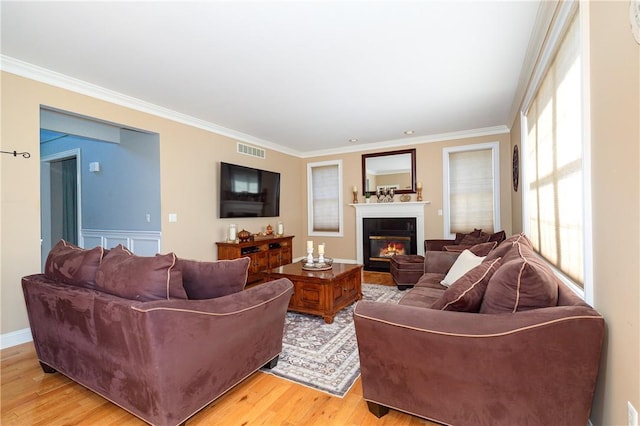 living room featuring a wealth of natural light, crown molding, and light hardwood / wood-style floors