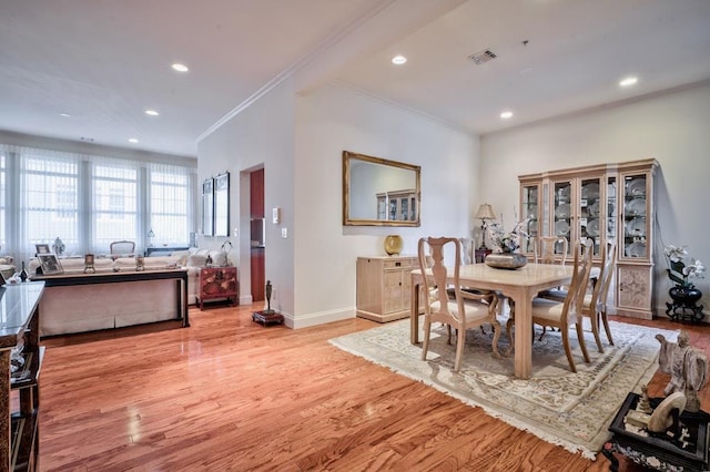 dining area featuring ornamental molding and light hardwood / wood-style flooring