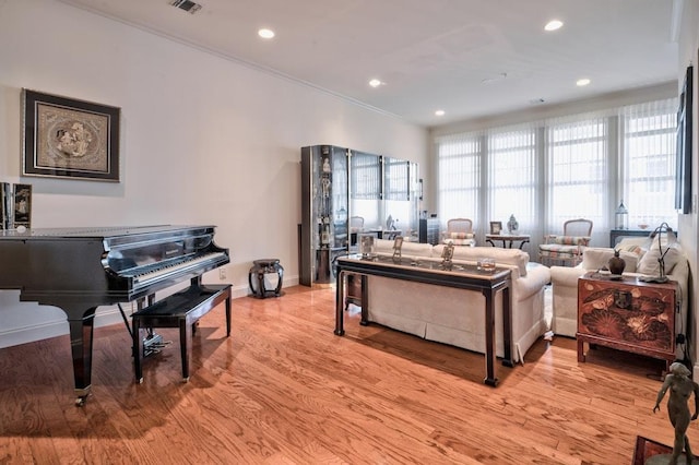 living room with light wood-type flooring and ornamental molding