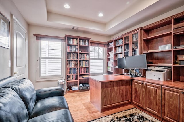 office featuring light wood-type flooring and a tray ceiling