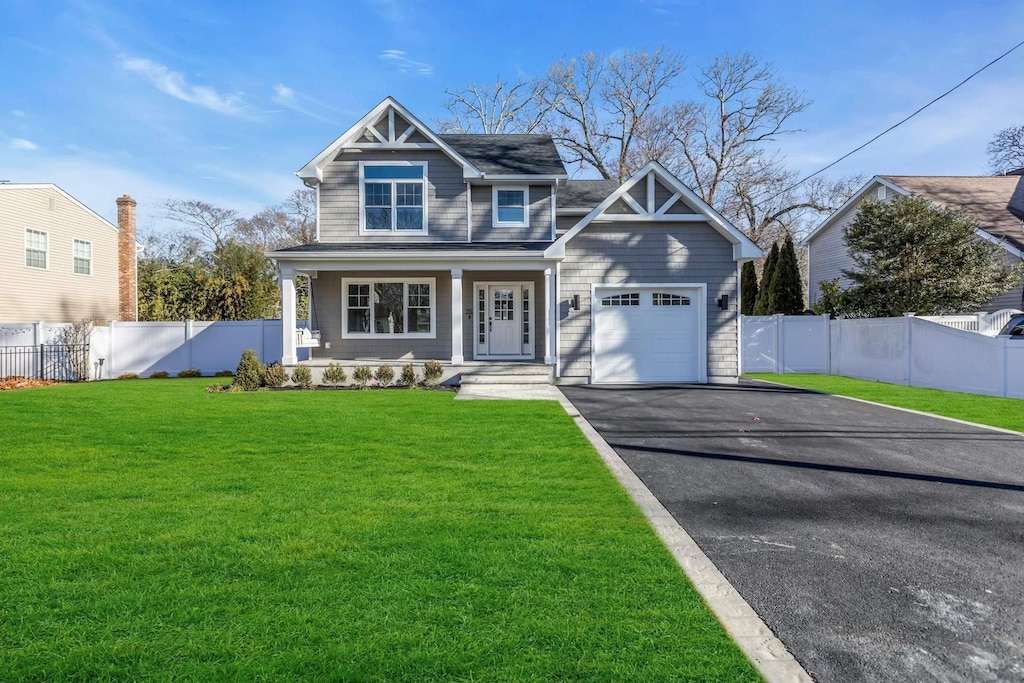 craftsman-style home featuring covered porch, a front yard, and a garage