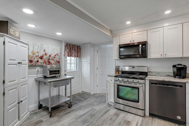 kitchen with appliances with stainless steel finishes, tasteful backsplash, crown molding, light hardwood / wood-style flooring, and white cabinetry