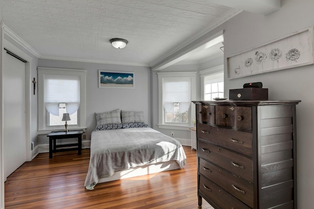 bedroom featuring a textured ceiling, hardwood / wood-style flooring, and ornamental molding