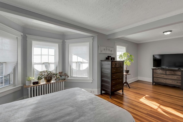 bedroom with hardwood / wood-style floors, a textured ceiling, radiator, and ornamental molding