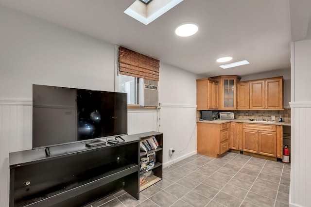 kitchen with tasteful backsplash, a skylight, sink, and light tile patterned floors