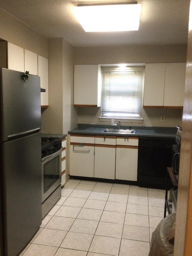 kitchen with stainless steel appliances, sink, light tile patterned floors, and white cabinets