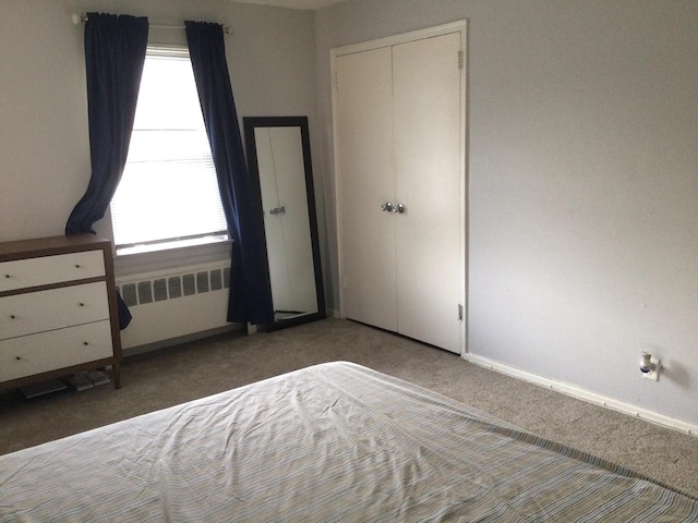 unfurnished bedroom featuring a closet, radiator heating unit, dark carpet, and multiple windows