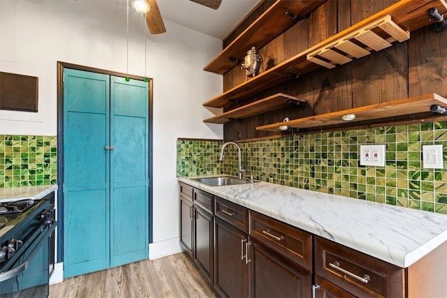 kitchen with black gas range, sink, ceiling fan, light hardwood / wood-style floors, and dark brown cabinetry