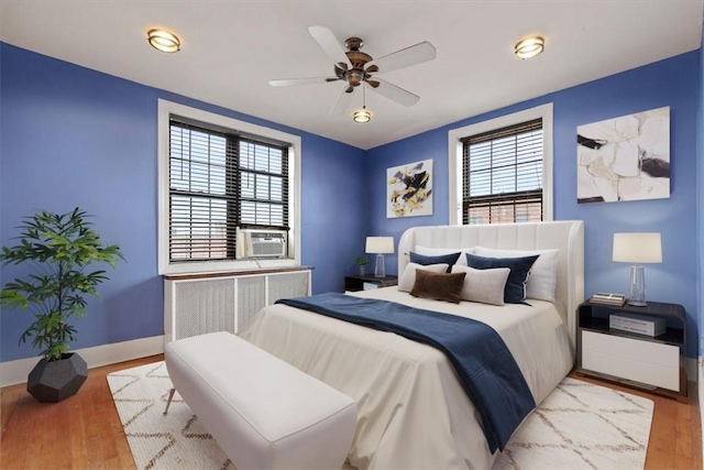 bedroom featuring radiator, ceiling fan, cooling unit, and light hardwood / wood-style floors