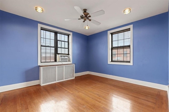 unfurnished room featuring wood-type flooring, ceiling fan, cooling unit, and radiator