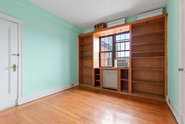 unfurnished room featuring cooling unit, light wood-type flooring, and radiator