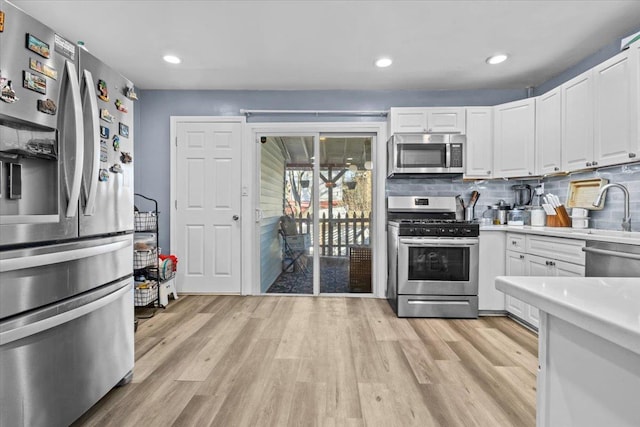 kitchen featuring tasteful backsplash, white cabinets, stainless steel appliances, and light wood-type flooring