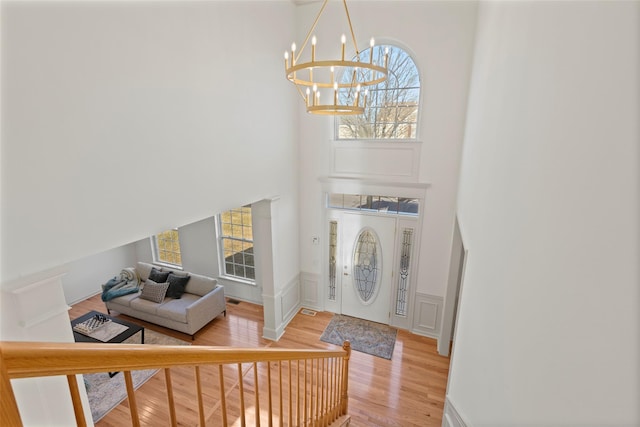 entryway with a high ceiling, hardwood / wood-style floors, and an inviting chandelier