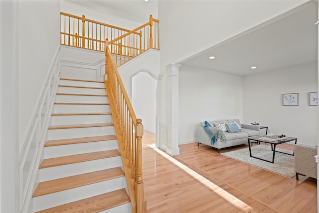 staircase with hardwood / wood-style flooring and ornate columns