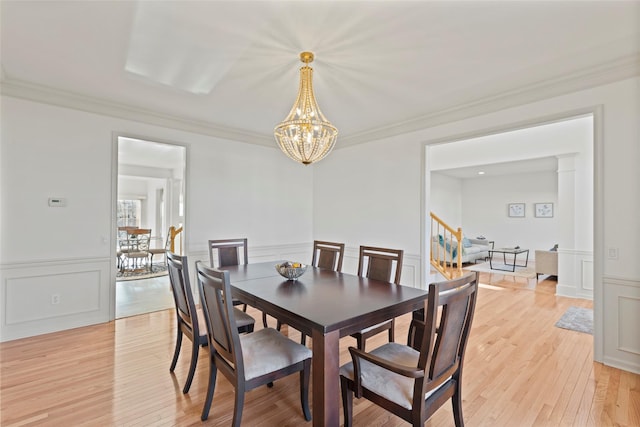 dining space with ornamental molding, light hardwood / wood-style flooring, and a notable chandelier