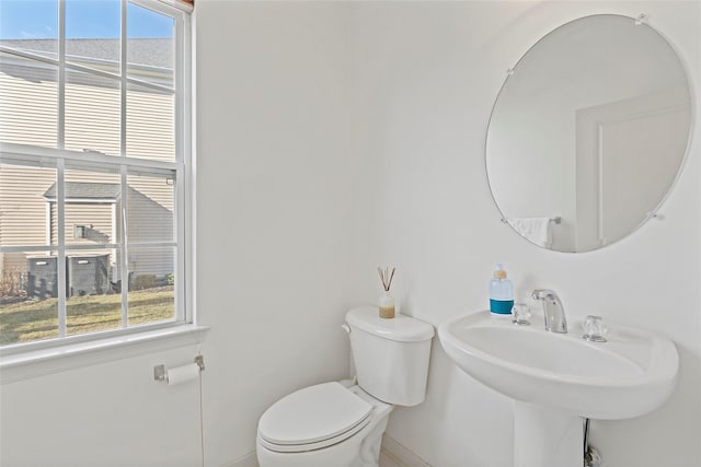 bathroom with a healthy amount of sunlight, toilet, and sink