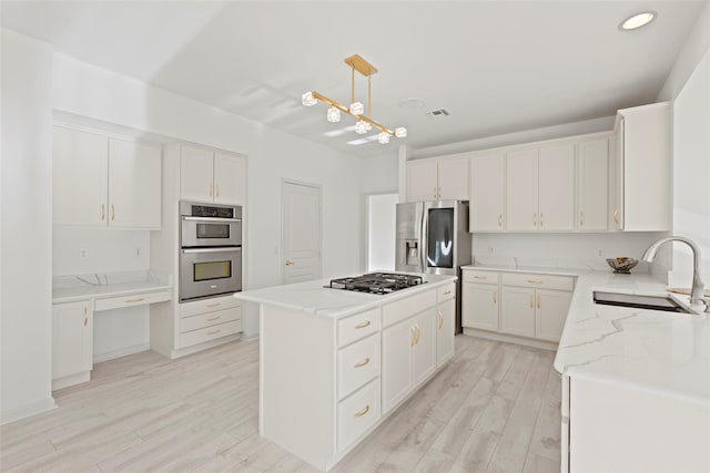 kitchen with a kitchen island, appliances with stainless steel finishes, pendant lighting, sink, and white cabinets