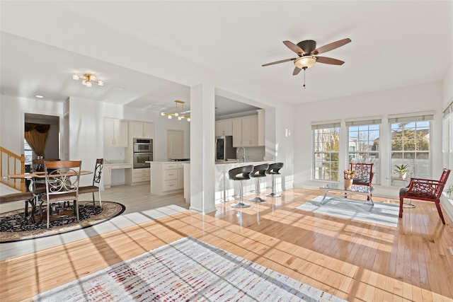 living room featuring sink, light hardwood / wood-style flooring, and ceiling fan