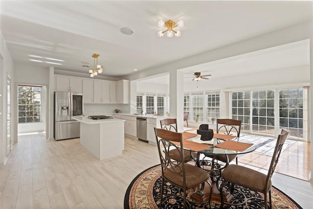 dining room featuring ceiling fan with notable chandelier and light wood-type flooring