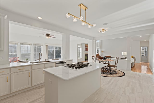 kitchen with pendant lighting, sink, appliances with stainless steel finishes, white cabinets, and a kitchen island