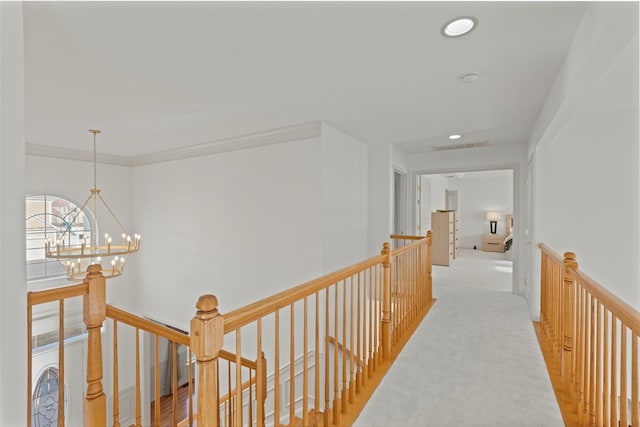 hall featuring ornamental molding, light carpet, and an inviting chandelier