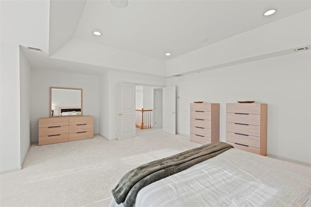 bedroom with light colored carpet and a raised ceiling