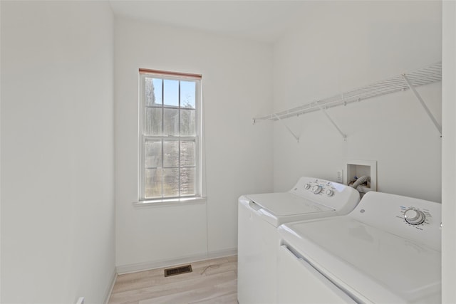 laundry room with light hardwood / wood-style floors and washer and dryer