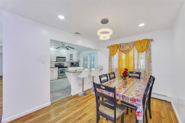 dining room featuring baseboard heating, ceiling fan with notable chandelier, and light wood-type flooring