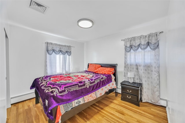 bedroom with hardwood / wood-style floors and a baseboard radiator