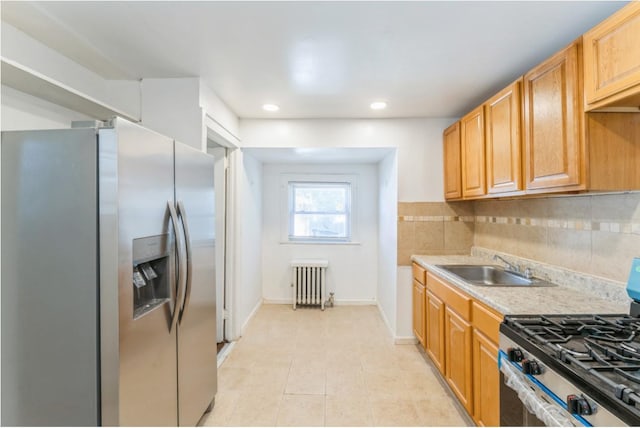 kitchen with light tile patterned floors, backsplash, appliances with stainless steel finishes, radiator heating unit, and sink