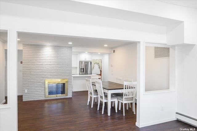 dining room featuring dark hardwood / wood-style flooring, a brick fireplace, and a baseboard heating unit