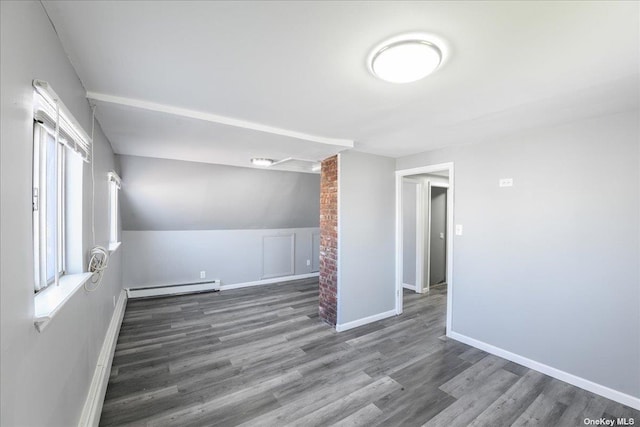 empty room featuring plenty of natural light, dark wood-type flooring, and a baseboard radiator