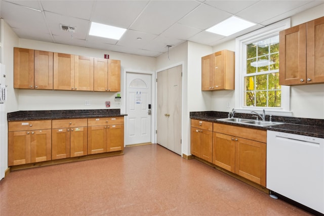 kitchen featuring sink, a paneled ceiling, dark stone counters, and dishwasher