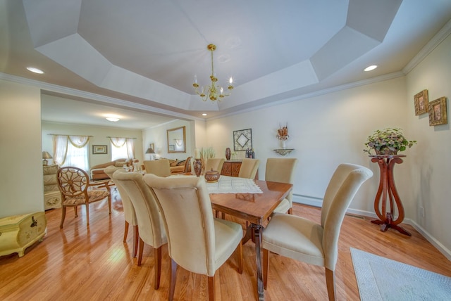 dining area with a notable chandelier, light hardwood / wood-style flooring, and a tray ceiling