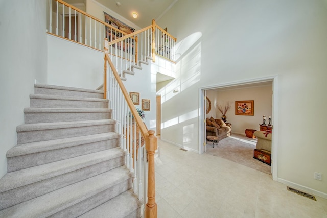 staircase featuring crown molding and a towering ceiling