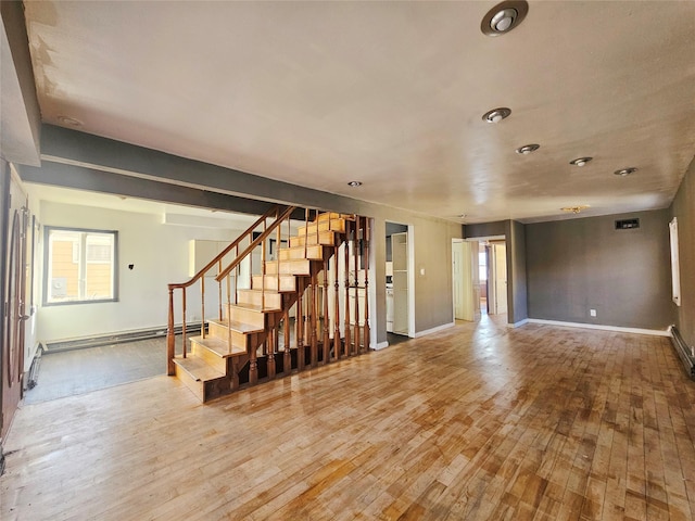 unfurnished living room with baseboard heating and light hardwood / wood-style floors