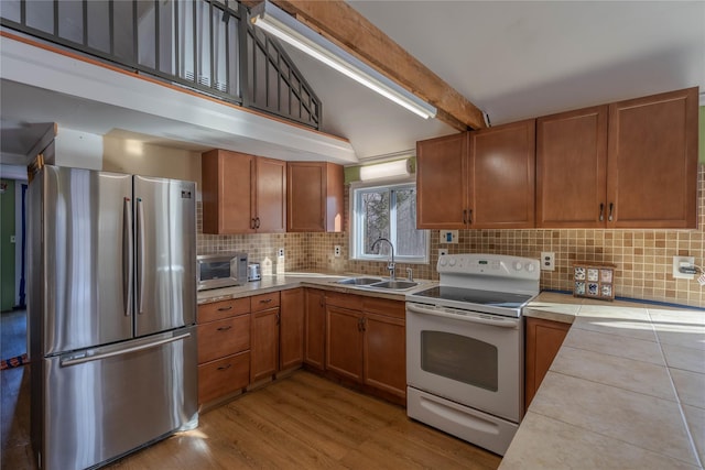 kitchen featuring decorative backsplash, sink, tile countertops, white range with electric cooktop, and stainless steel refrigerator