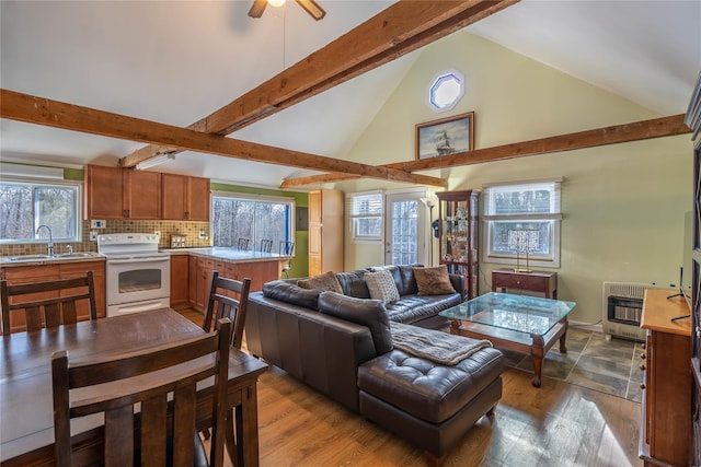 living room with beam ceiling, heating unit, sink, and light hardwood / wood-style floors