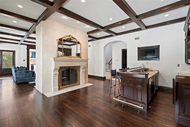 kitchen with kitchen peninsula, dark hardwood / wood-style flooring, coffered ceiling, beamed ceiling, and a breakfast bar area