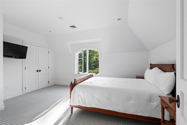 carpeted bedroom with a closet and vaulted ceiling