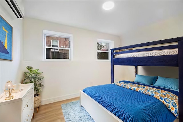 bedroom featuring a wall mounted air conditioner and light hardwood / wood-style floors