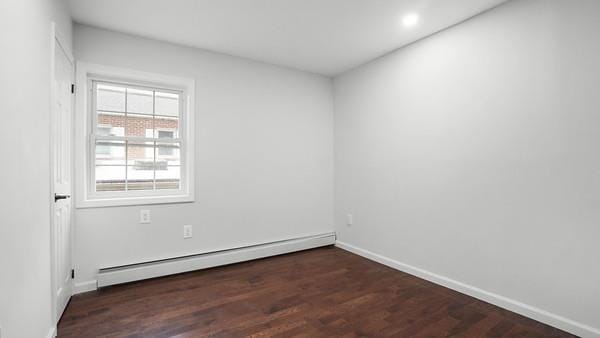 empty room with dark hardwood / wood-style floors and a baseboard heating unit