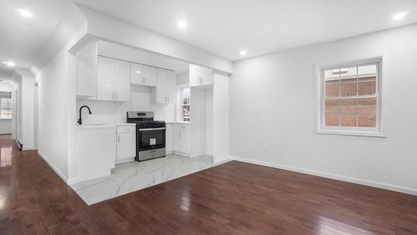 kitchen with stainless steel range, white cabinets, light hardwood / wood-style floors, and sink