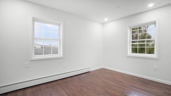 unfurnished room with dark wood-type flooring and a baseboard heating unit