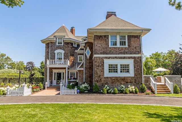 view of front of house with a balcony and a front lawn