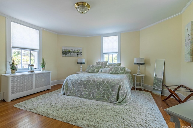 bedroom featuring radiator heating unit, hardwood / wood-style flooring, and ornamental molding