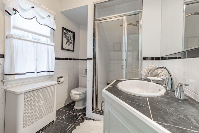 bathroom featuring radiator heating unit, vanity, a wealth of natural light, and tile walls