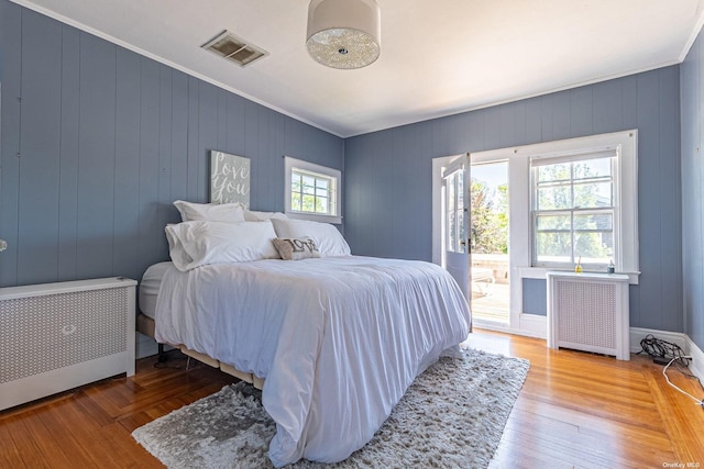 bedroom featuring radiator heating unit, hardwood / wood-style flooring, and multiple windows