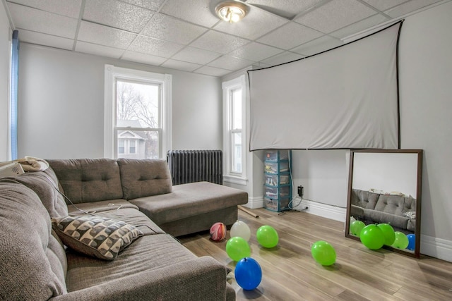 living room featuring wood-type flooring, radiator, and a paneled ceiling